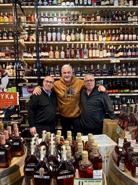 Chuck Swaney with the owners and bottles of whiskey at The Wine Palace in Livonia, MI.